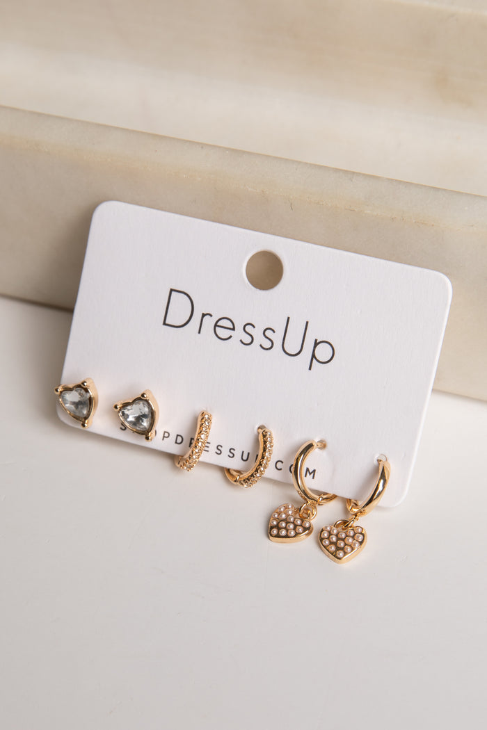 Set of gold earrings on a 'DressUp' branded card against a beige background