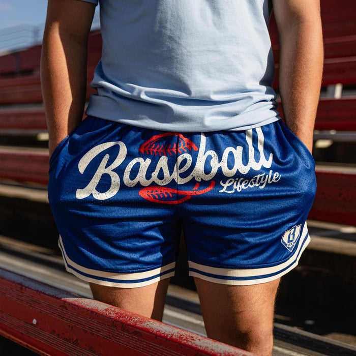 Close up of royal blue Baseball Lifestyle mesh shorts with white script graphic red baseball lace detail and white striped hem