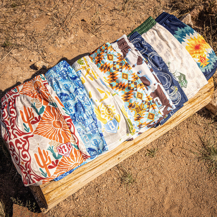 Seven pairs of patterned boxer briefs on a wooden block against a natural background