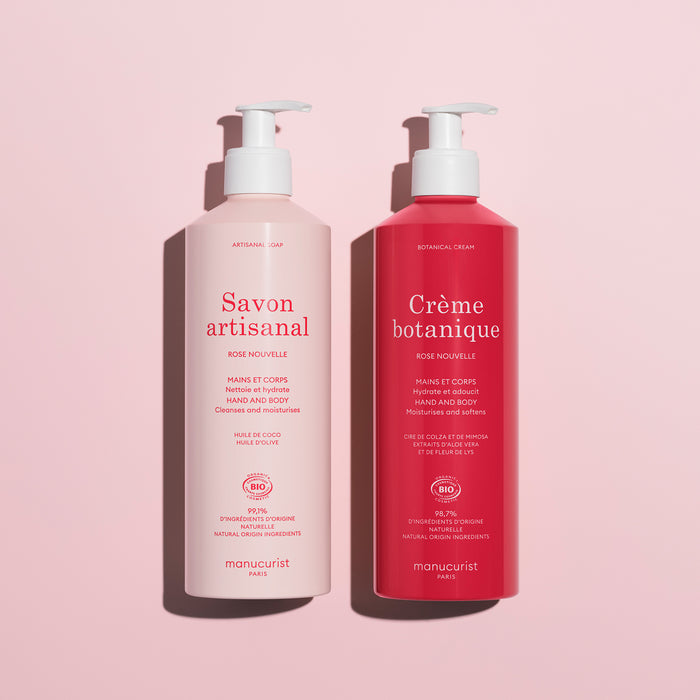 Two pump bottles on a pink background: the left is light pink labeled Savon artisanal, and the right is dark pink labeled Soothing Rose Hand Body Cream - Cosmos Organic by Manucurist, a deeply hydrating hand and body product.