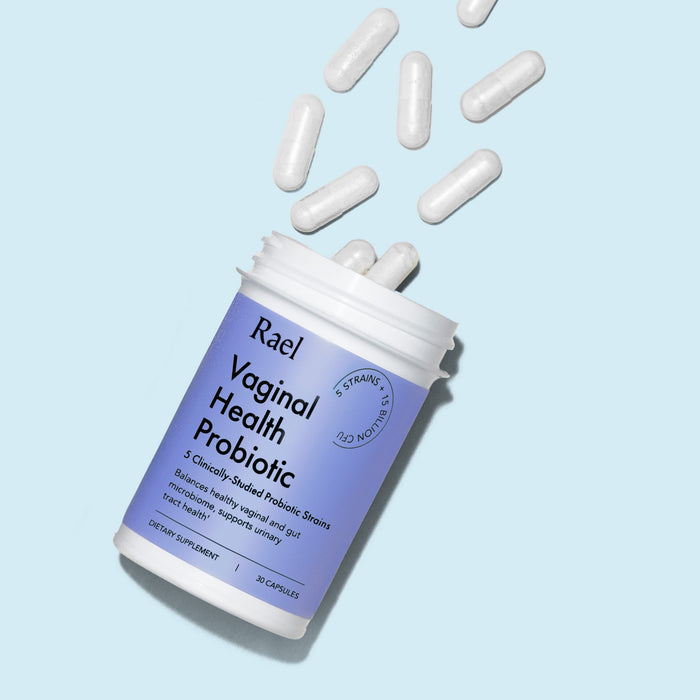 Vaginal Health Probiotic by Rael coming out of bottle, on a light blue background.