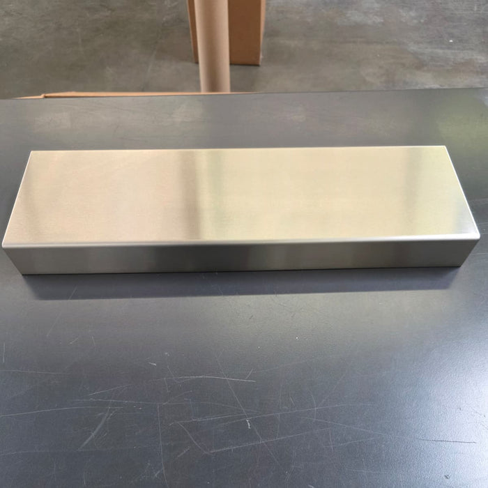 Long stainless steel display riser on a dark worktable.