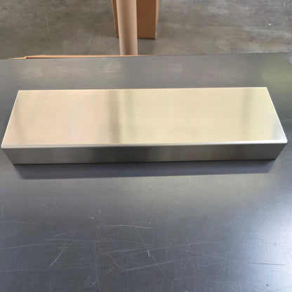 Long stainless steel display riser on a dark worktable.