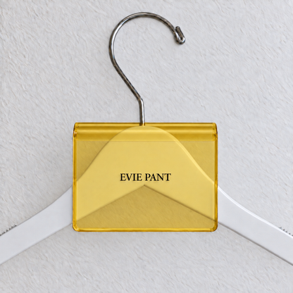 Yellow transparent acrylic hanger sign clip with soft edge reflections, resting on a white wooden hanger, with example EVIE PANT print