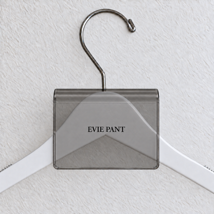 Gray Smoke acrylic hanger sign clip with soft edge reflections, resting on a white wooden hanger, with example EVIE PANT print