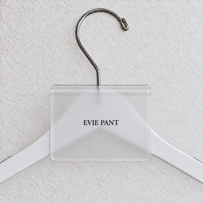Clear Matte acrylic hanger sign clip with soft edge reflections, resting on a white wooden hanger, with example EVIE PANT print