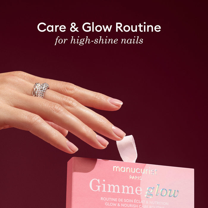 A hand with glossy, manicured nails and a jeweled ring holds a pink Manucurist 5min' Glow Manicure box against a burgundy background, resembling a festive Christmas ornament. Above, text reads: Care  Glow Routine for high-shine nails.
