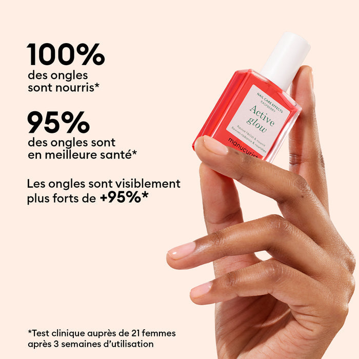 A hand holds Manucurist's 5min' Glow Manicure pink polish, delivering 100% nourished nails. French text notes 95% healthier, visibly stronger nails after 3 weeks—ideal for a festive holiday look, just like a Christmas ornament.