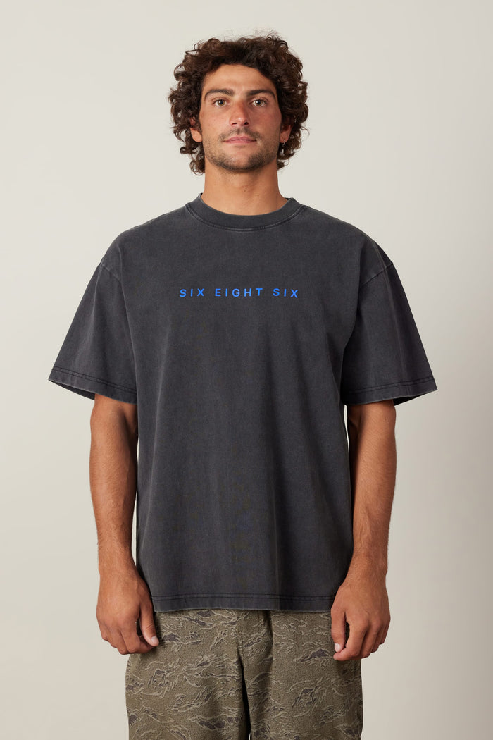 A man wearing the 686 Elements Relaxed S/S Tee, a classic black cotton t-shirt by 686.