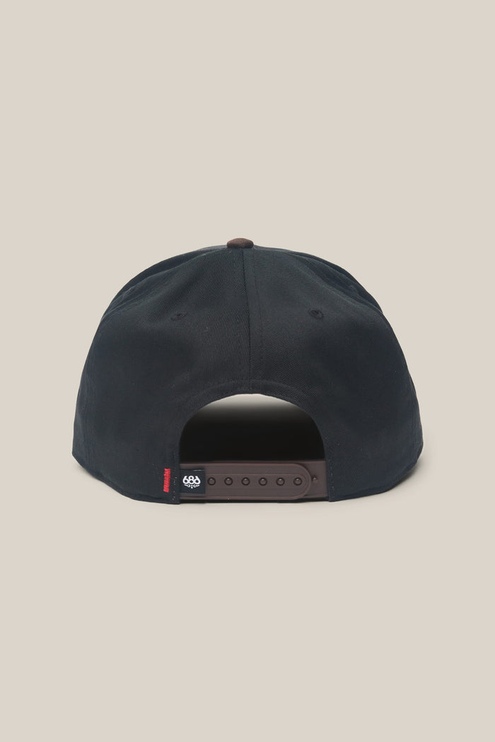 The 686 High-Pro Ses Two Tone Structured 5 Panel Hat by 686 is shown from the back, highlighting its adjustable brown strap and a small black fabric tag featuring white and red details. Made from quality cotton for lasting comfort and durability, this classic men's hat is photographed against a plain light beige background.