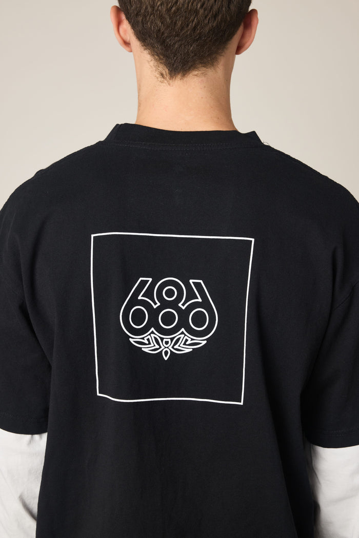 A person shown from behind wears the 686 Wordmark Relaxed 2fer LS Tee, a black 100% cotton men‚Äôs t-shirt by 686, featuring a white outlined square with the 686 logo and graphic design on the back, complementing their short brown hair.