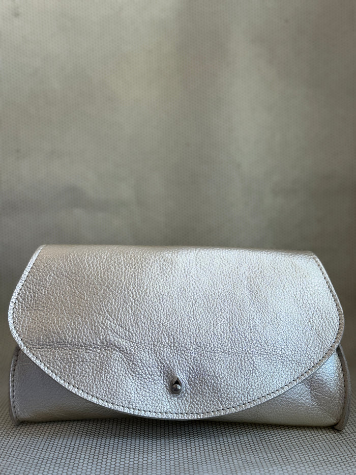 silver Dean leather clutch bag on a textured surface.