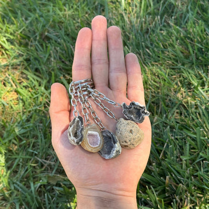 Hand holding a set of geode necklaces against a grassy background