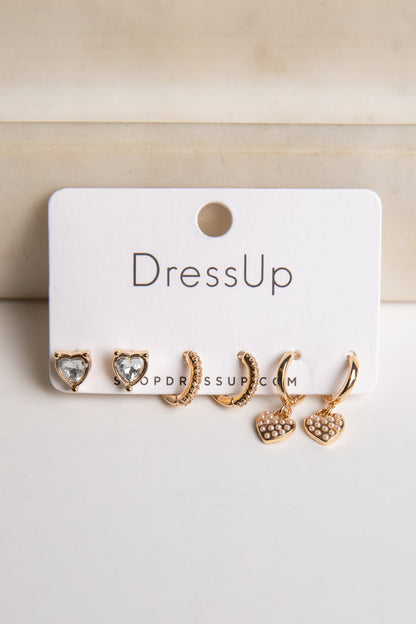 Set of gold earrings on a 'DressUp' branded card against a beige background