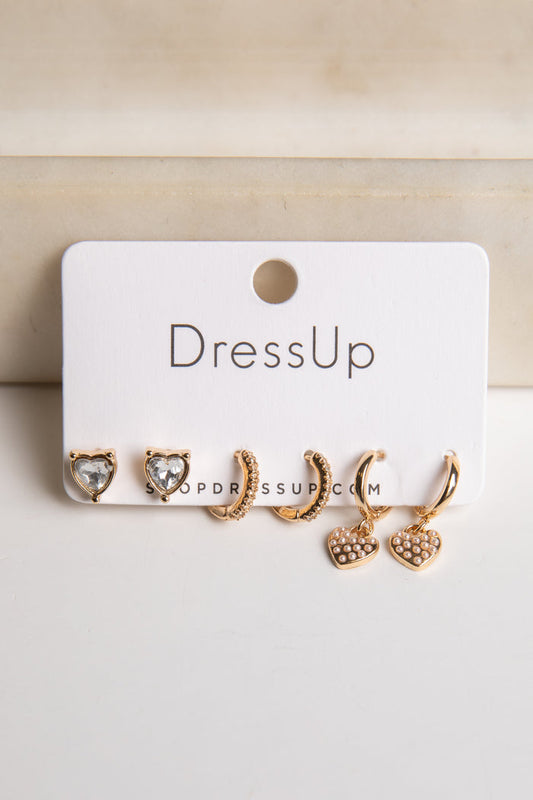 Set of gold earrings on a 'DressUp' branded card against a beige background