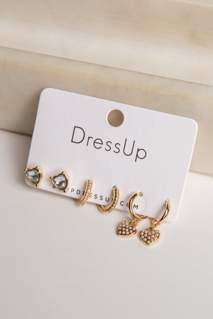Set of gold earrings on a 'DressUp' branded card against a beige background