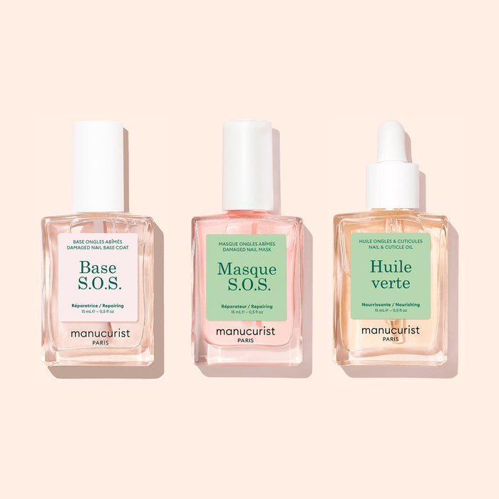 Three square bottles from Manucurist’s Basic Routine - Damaged Nails set are displayed with pastel backgrounds and white caps—one topped with a dropper. The labels read: Base S.O.S., Masque S.O.S., and Huile Verte, each formulated to strengthen and repair brittle nails.