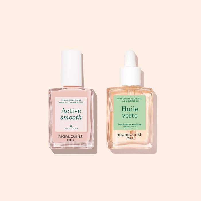 Two square glass bottles from manucurist’s Basic Routine - Ridged Nails set, each with a white cap, labeled Active Smooth (containing pink liquid) and Huile Verte (with yellow liquid), stand side by side on a pale peach background. Specially designed for nail care, these products are ideal for nourishing and smoothing ridged nails and can also be used as cuticle oil to keep nails healthy.