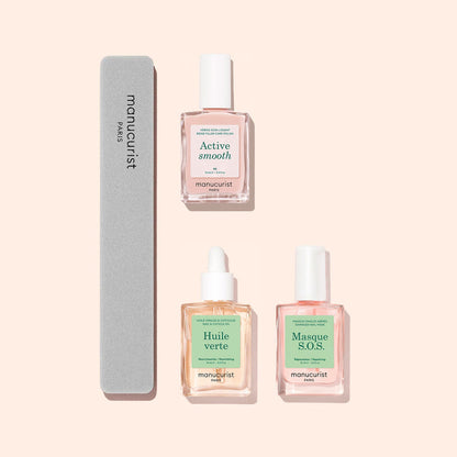 Three glass bottles from the Manucurist Basic Routine - Ridged Nails set, along with a gray nail file, are arranged neatly on a light peach background—perfect for your daily nail care ritual. The bottles include Active Smooth, Huile Verte (a nourishing cuticle oil), and Masque S.O.S., all specially formulated to restore strength to ridged nails and promote overall nail health.