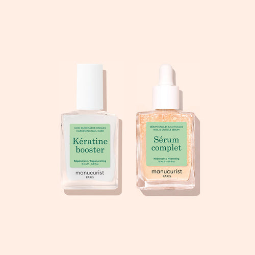 Two clear glass bottles from Manucurist’s Basic Routine - Soft Nails set are displayed on a beige background. The bottle on the left is labeled Kératine Booster, while the bottle on the right features a dropper and is labeled Sérum Complet. Both manicure care products are perfect for enhancing your nail care routine, making them ideal for anyone looking to restore and strengthen soft nails.