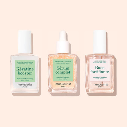 Three square glass bottles from Manucurist’s "Basic Routine - Soft Nails" set are arranged side by side on a light beige background. Designed for your nail care routine, each bottle features a white cap and a distinct label—Kératine booster, Sérum complet, and Base fortifiante—making this Manucurist collection ideal for anyone with soft nails seeking an effective strengthening solution.