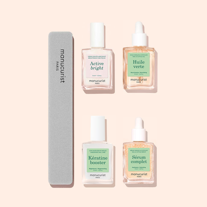 Four products from the Manucurist Ultimate Routine - Yellow Nails set and a gray nail file are arranged neatly on a light beige background. Ideal for nail strengthening and brightening, the set includes Active Bright, Huile Verte, Kératine Booster, and Sérum Complet in clear bottles.