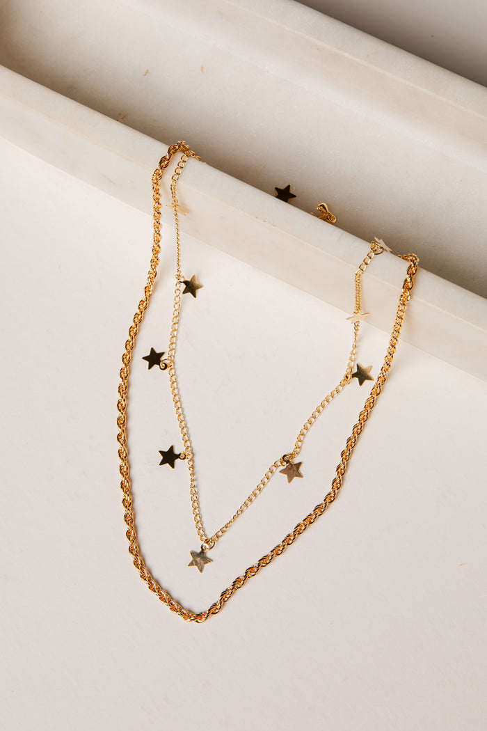 Gold necklace with star pendants on a marble surface