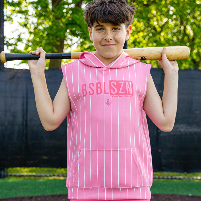 Youth player holding a bat over his shoulders wearing the pink pinstripe Jackson Olson x BL101 BSBL-SZN Short Sleeve Hoodie V3