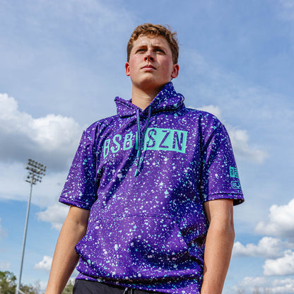 Youth model wearing splatter purple and teal BSBL-SZN youth short sleeve hoodie