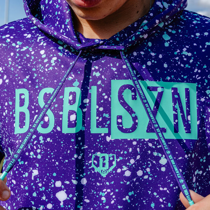 Youth model wearing splatter purple and teal BSBL-SZN youth short sleeve hoodie