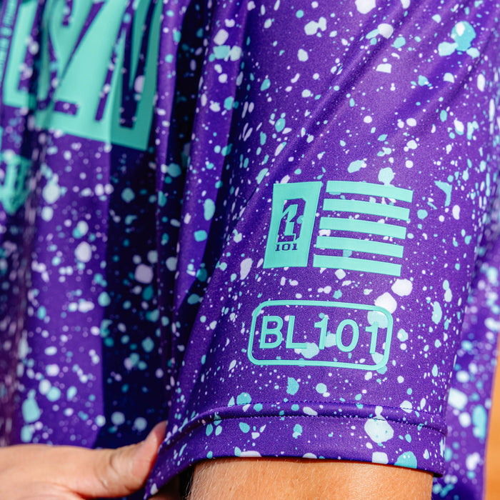 Youth model wearing splatter purple and teal BSBL-SZN youth short sleeve hoodie