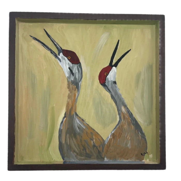 A painting of two cranes with a wood frame.