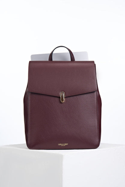 Front view of Casey Black Cherry faux leather Laptop Backpack showing resin Waterloo Twist Lock closure on the front flap and a laptop in the back pocket