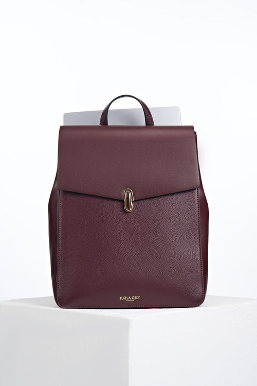 Front view of Casey Black Cherry faux leather Laptop Backpack showing resin Waterloo Twist Lock closure on the front flap and a laptop in the back pocket