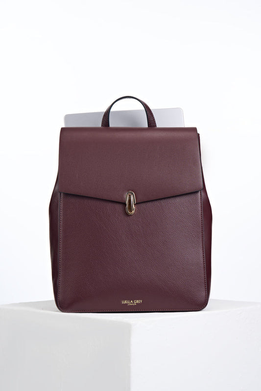 Front view of Casey Black Cherry faux leather Laptop Backpack showing resin Waterloo Twist Lock closure on the front flap and a laptop in the back pocket