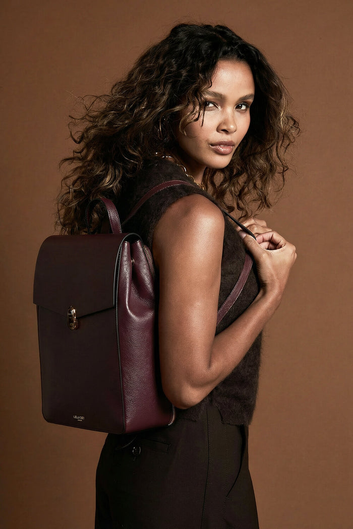 Female model wearing Casey Black Cherry faux leather Laptop Backpack using both straps over her shoulders showing the front of the backpack