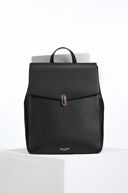 Front view of Casey Black faux leather Laptop Backpack showing resin Waterloo Twist Lock closure on the front flap and a laptop in the back pocket
