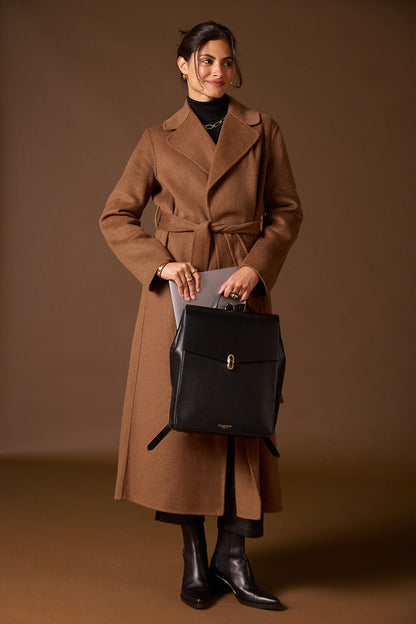Female model taking a laptop out of the back laptop pocket of Casey Black faux leather Laptop Backpack