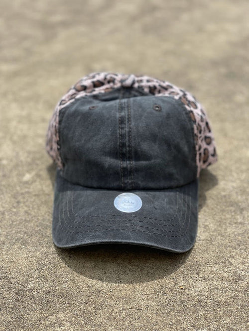Distressed black cap with a brown leopard print back.  The back has elastic crisscrossing bands and a adjustable Velcro back for a truly adjustable fit for your ponytails or buns. Front View