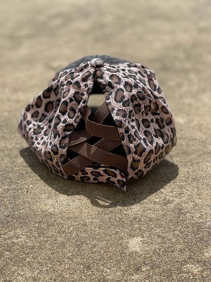 Distressed black cap with a brown leopard print back.  The back has elastic crisscrossing bands and a adjustable Velcro back for a truly adjustable fit for your ponytails or buns. Rear View