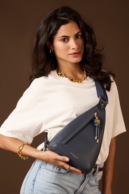 Female model wearing Darla Denim Blue faux leather Sling Crossbody across her body with the bag on her front
