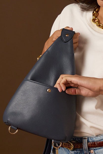 Female model opening the slip in pocket on the back of Darla Denim Blue faux leather Sling Crossbody