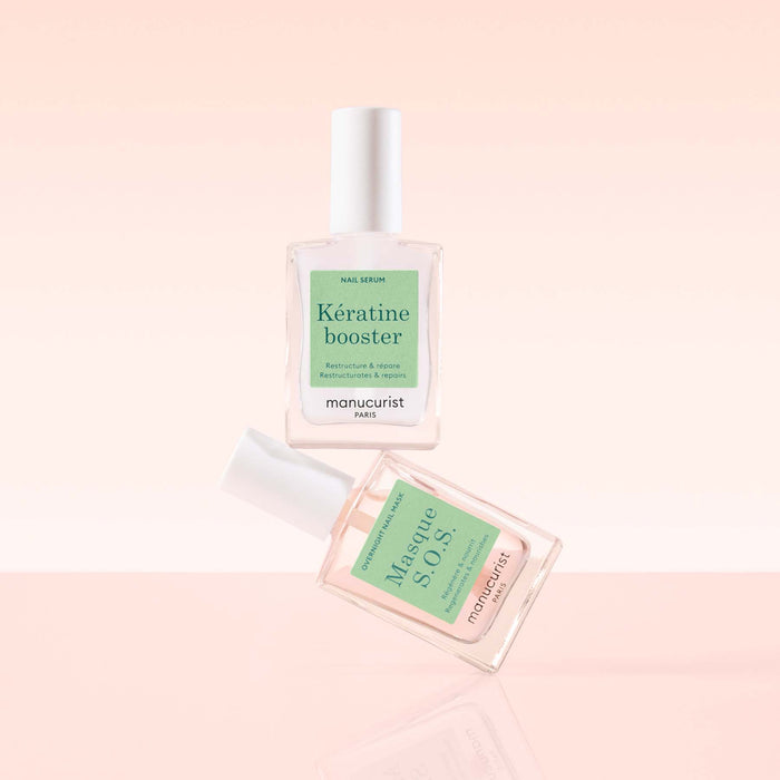 Two clear Manucurist Day  Night Duo nail care bottles with white caps are set against a soft pink background. The duo includes a keratin serum booster and Masque S.O.S nail mask, both for effective nail treatment.