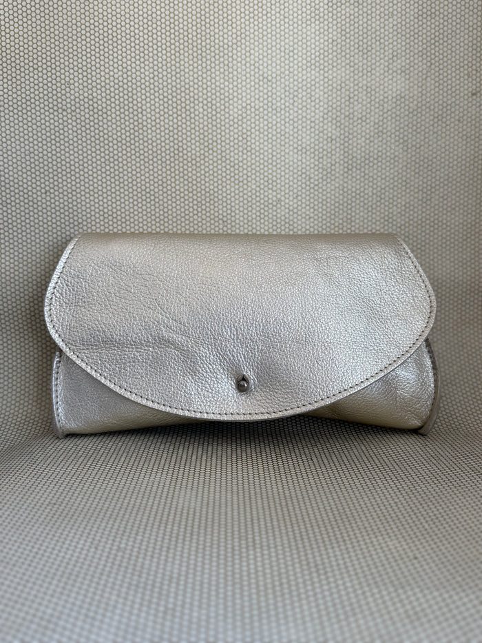 silver Dean leather clutch bag on a textured surface.