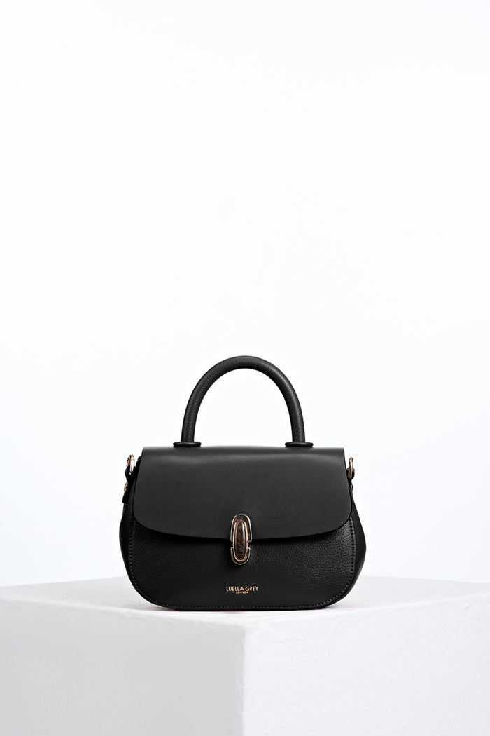 Front of Delia Black faux leather Top Handle Crossbody without detatchable crossbody strap showing resin Waterloo twist lock clasp closure detail