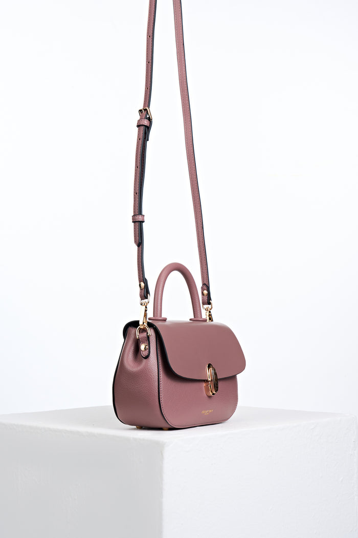 Side view of the  Delia Pecan faux leather Top Handle Crossbody with the crossbody handles attached to the gold hoops on the bag's side