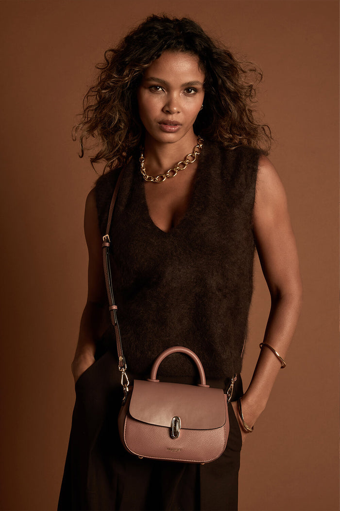 Female model wearing the Delia Pecan faux leather Top Handle Crossbody across her body using the crossbody strap