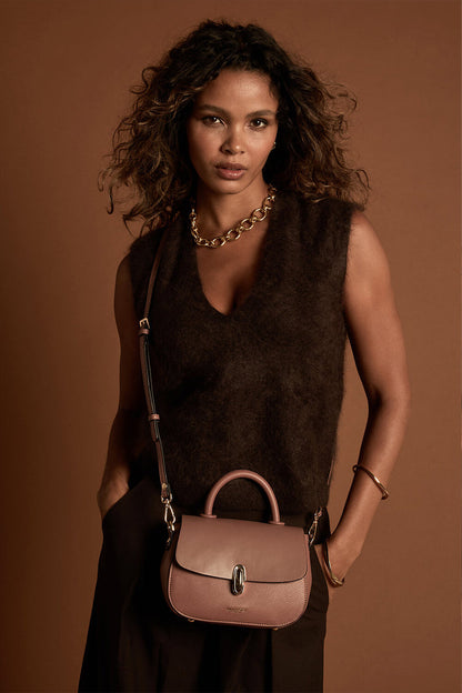 Female model wearing the Delia Pecan faux leather Top Handle Crossbody across her body using the crossbody strap