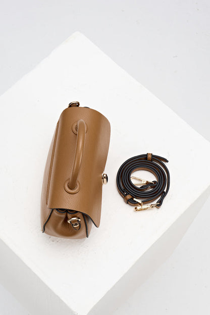 Overhead view of Delia Tan faux leather Top Handle Crossbody showing the top grab handle and the detachable crossbody strap rolled up beside the bag