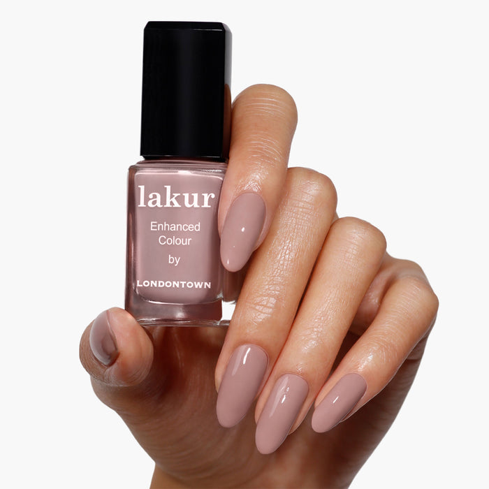 A hand with manicured nails painted in bold mauve matches a bottle of LONDONTOWN's "Do Not Disturb" nail polish set against a plain white background.